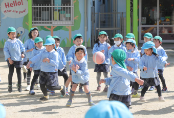 運動場でボール遊びをするこどもたち